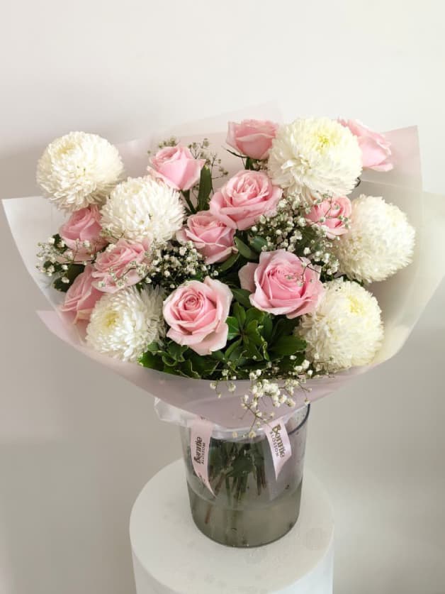 A soft pastel bouquet with pink roses and large white chrysanthemums