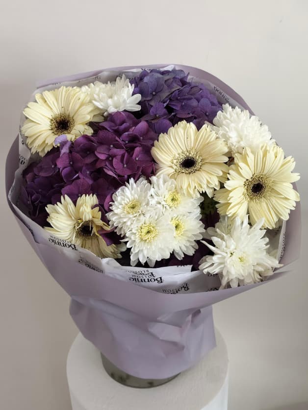 A contrasting bouquet of purple hydrangeas and white gerberas
